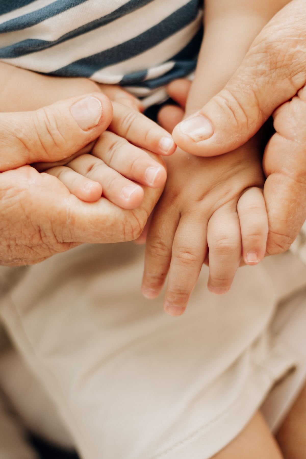 An elderly hand and a child's hand together, representing family succession